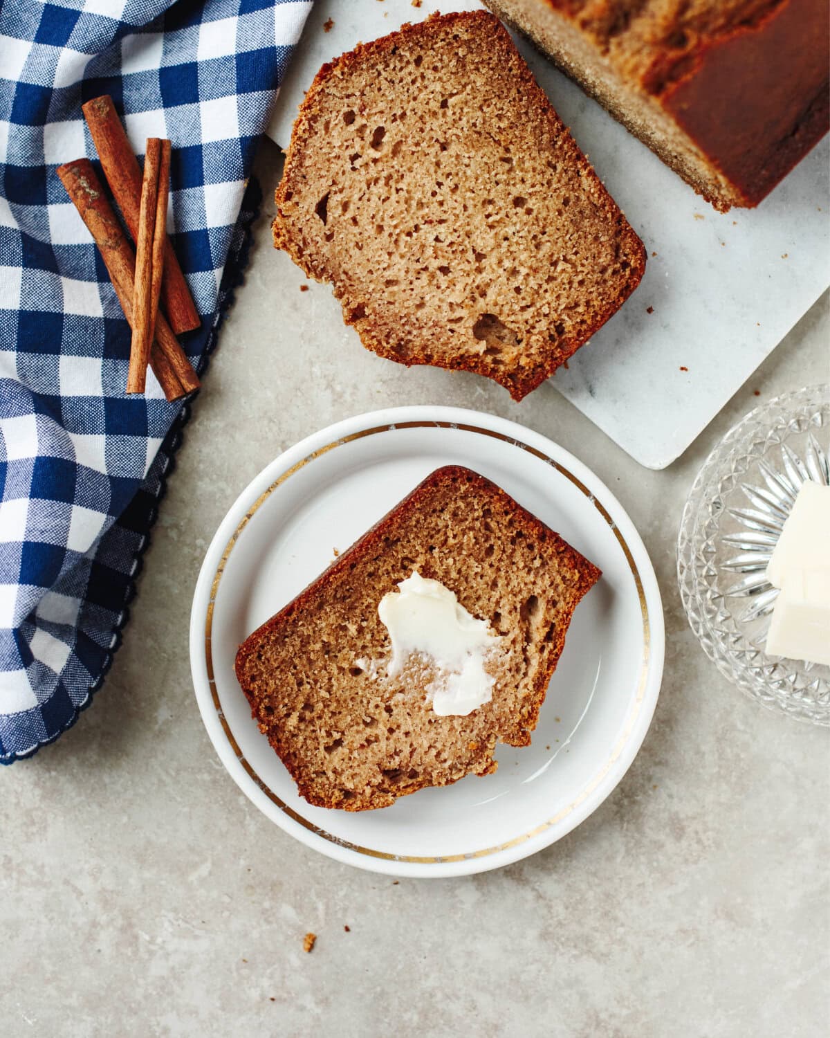 A buttered slice of applesauce bread on a white plate.