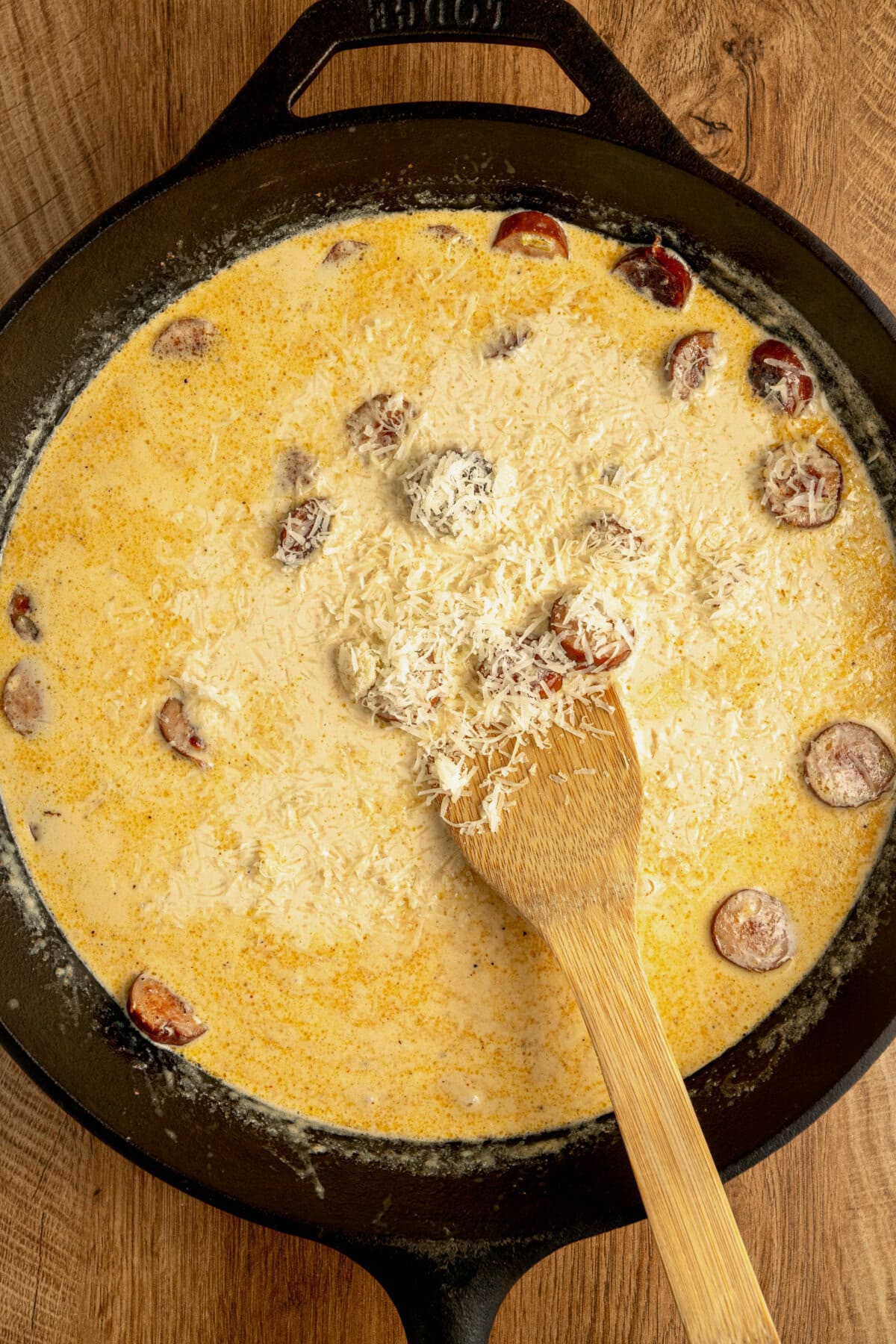 Parmesan cheese added to a creamy sauce in a cast iron skillet.