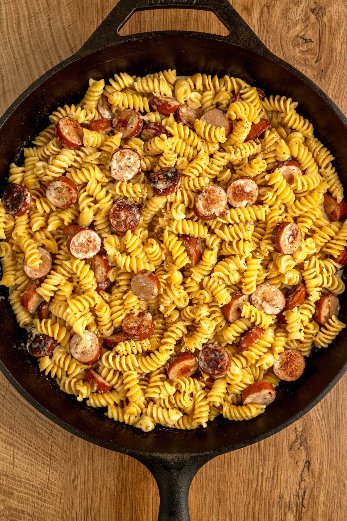 Tender pasta, smoked sausage, and a creamy spice sauce combined in a cast iron skillet.