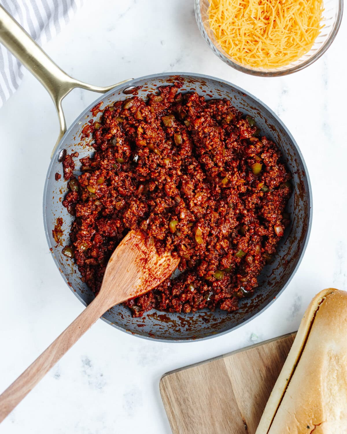Ground beef, peppers, onions, and ketchup combined in a skillet.