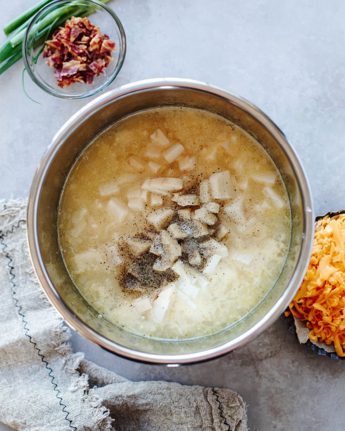 Potatoes, broth, seasonings, and cream added to an Instant Pot liner.