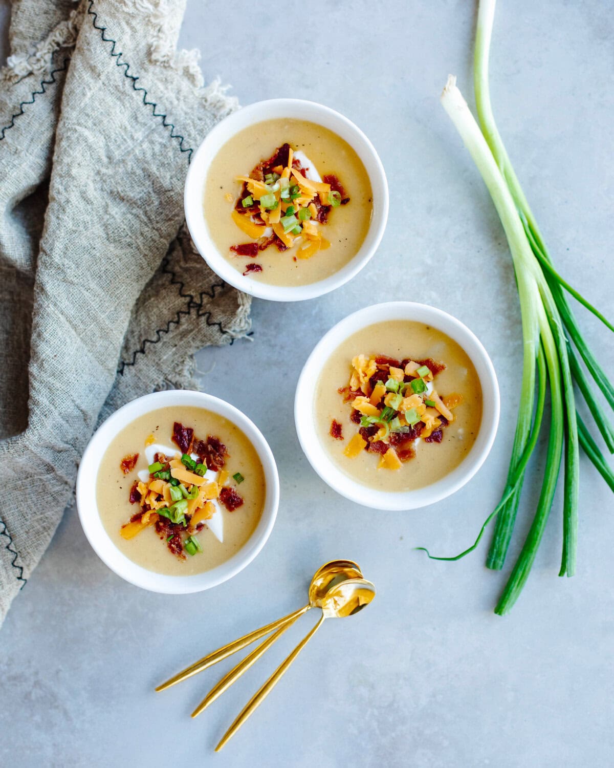 Three white soup bowls filled with Instant Pot Loaded Potato Soup ready to serve.
