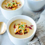 White soup bowls filled with loaded baked potato soup.