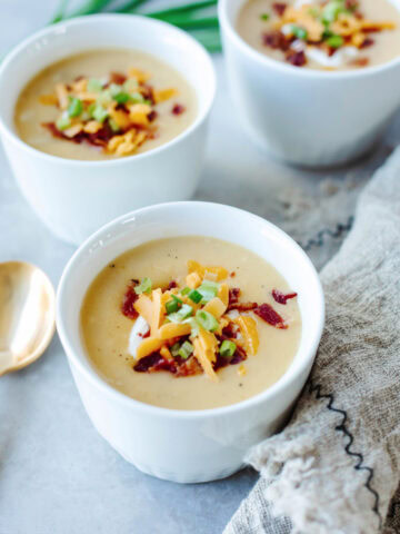 White soup bowls filled with loaded baked potato soup.