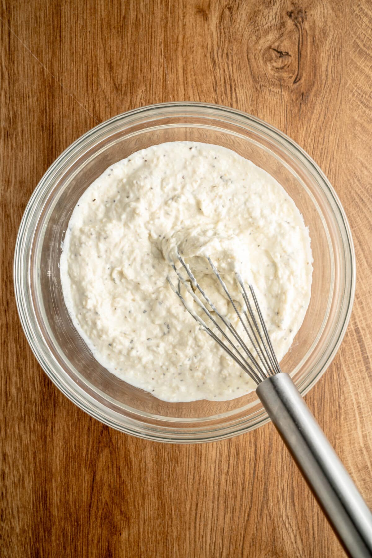 Mayonnaise, salt, pepper, garlic powder, and Parmesan cheese whisked together in a glass mixing bowl.