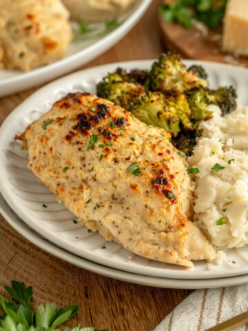 Melt in your mouth chicken on a dinner plate served with mashed potatoes and broccoli.