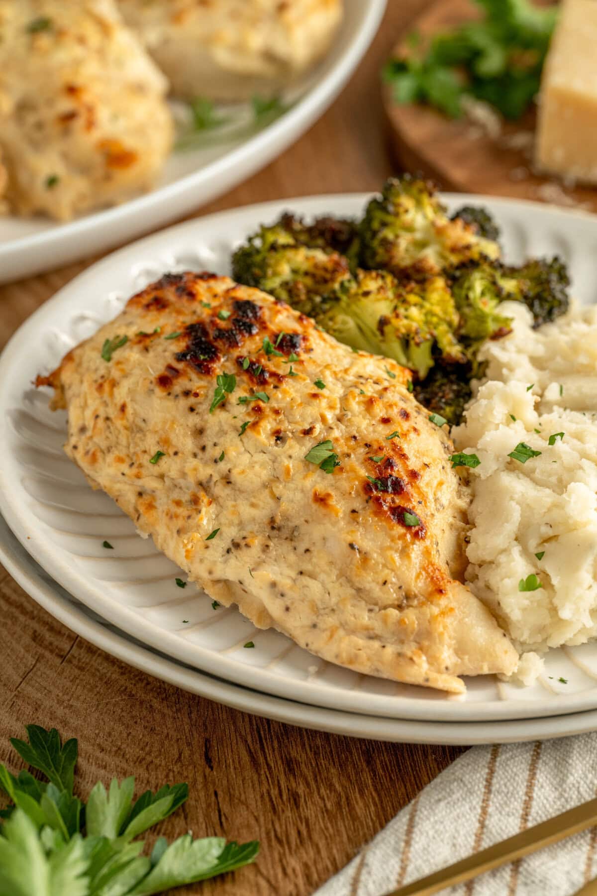 Melt in your mouth chicken on a dinner plate served with mashed potatoes and broccoli.