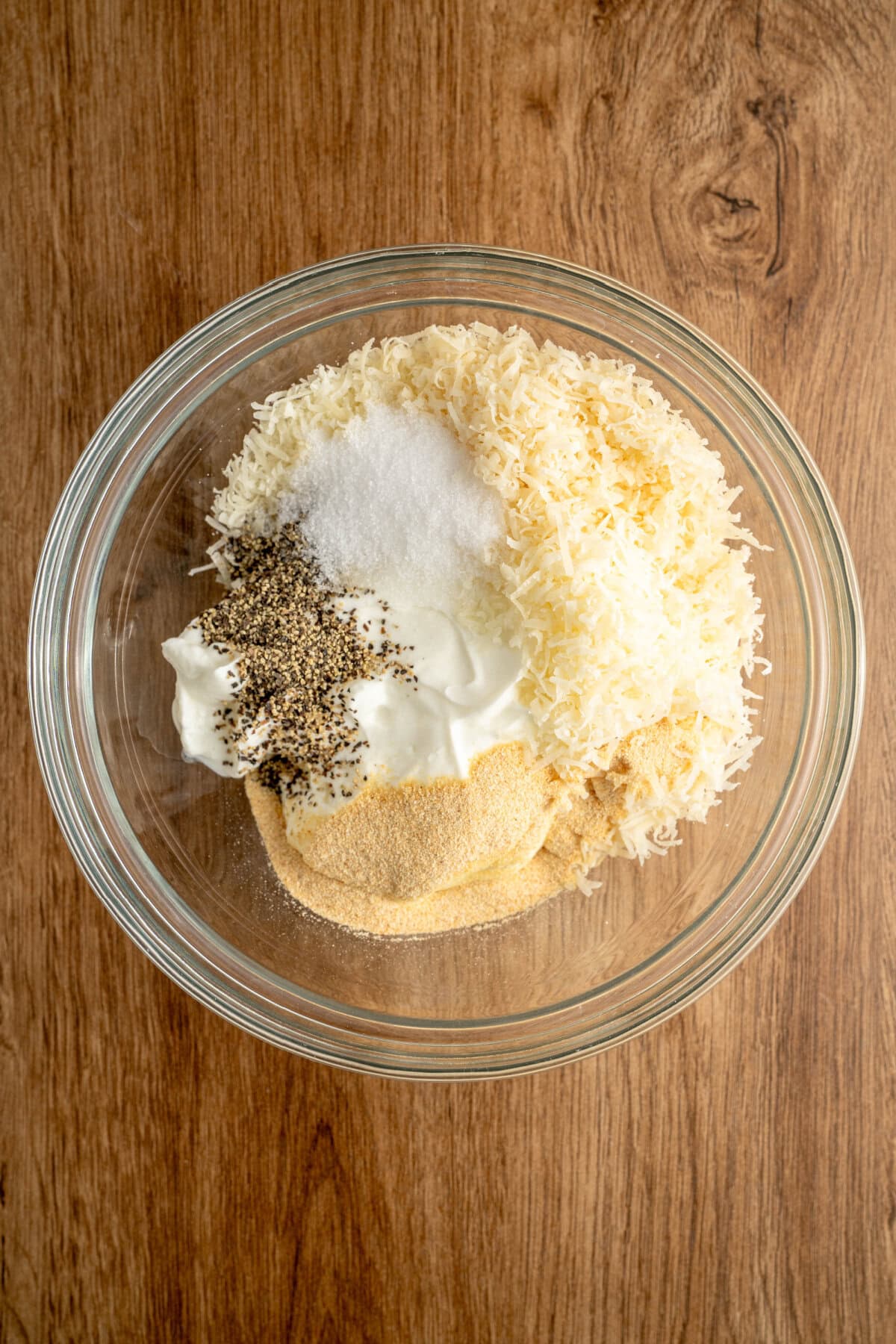 Garlic powder, salt, pepper, Parmesan, and mayonnaise added to a glass bowl.