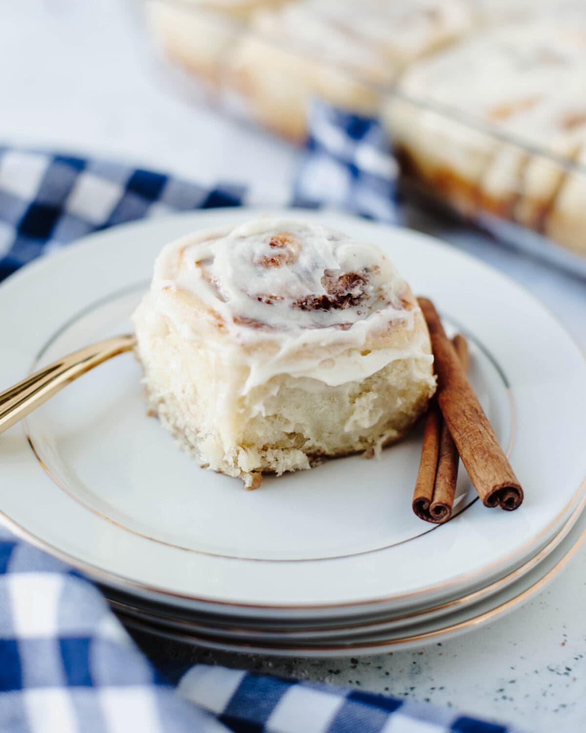 An individual cinnamon roll on a plate with cream cheese frosting.