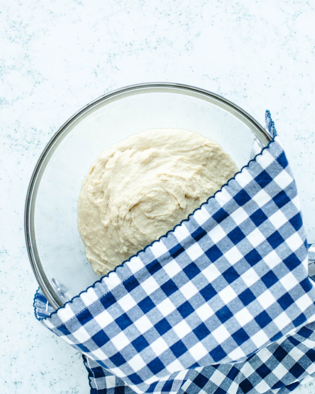 Cinnamon roll dough covered with a towel to rise for an hour.