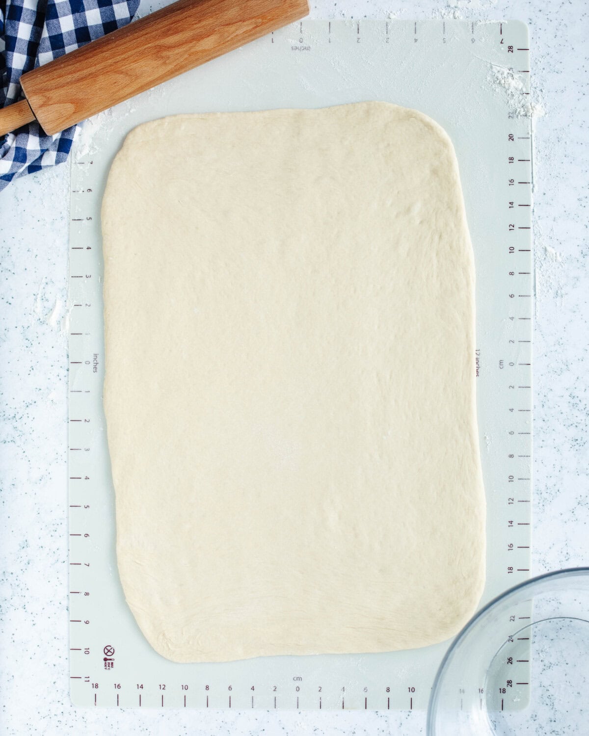 Homemade dough rolled out using a rolling pin on a cutting board.