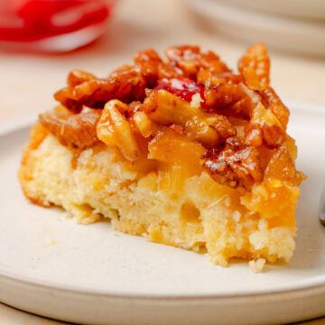 Slice of Pineapple Upside Down Cake showing the soft cake, caramelized pineapple, and walnut topping.