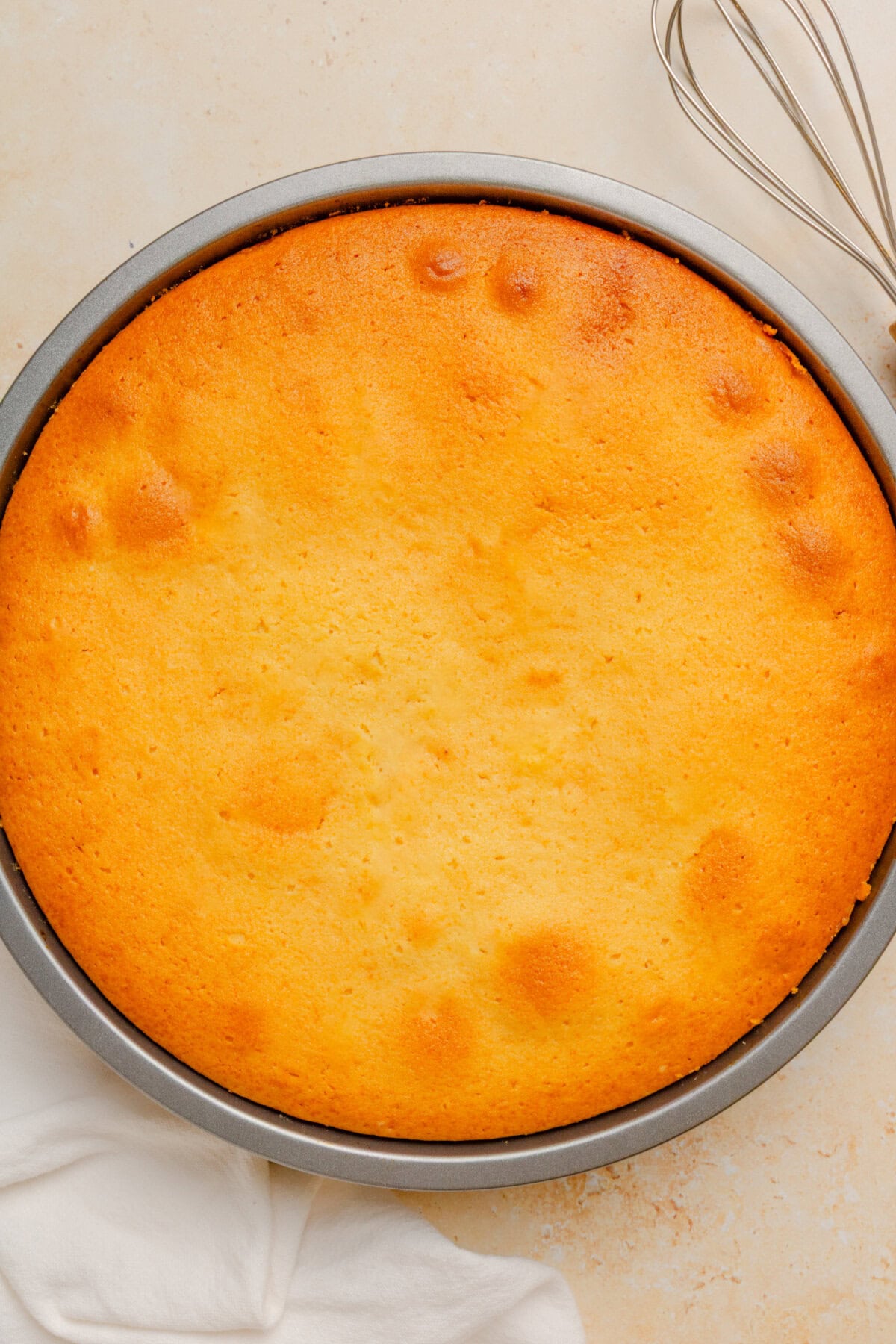 Freshly baked cake in a round cake pan before being inverted onto a serving plate.
