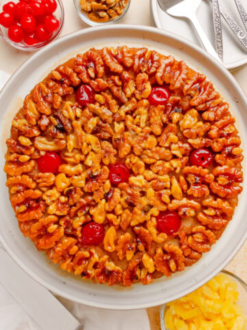 Old-fashioned Pineapple Upside Down Cake topped with walnuts, maraschino cherries, and pineapple.