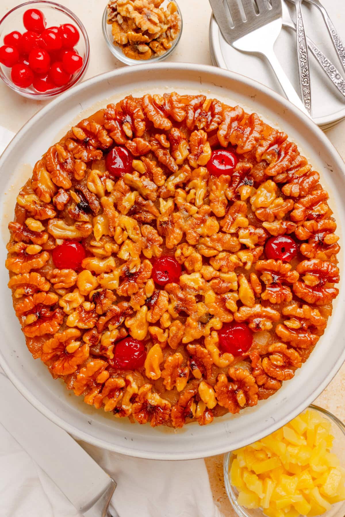 pineapple upside down cake with cherries on a white plate.