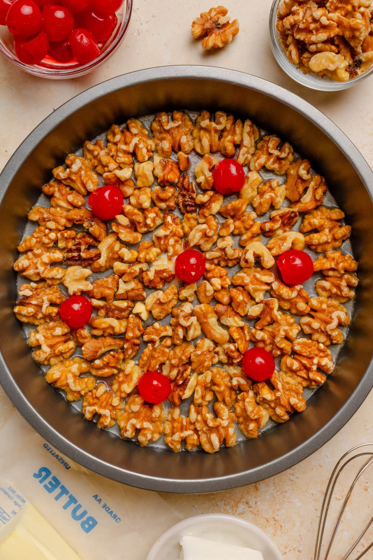 Walnuts and maraschino cherries arranged in melted butter before adding the topping.