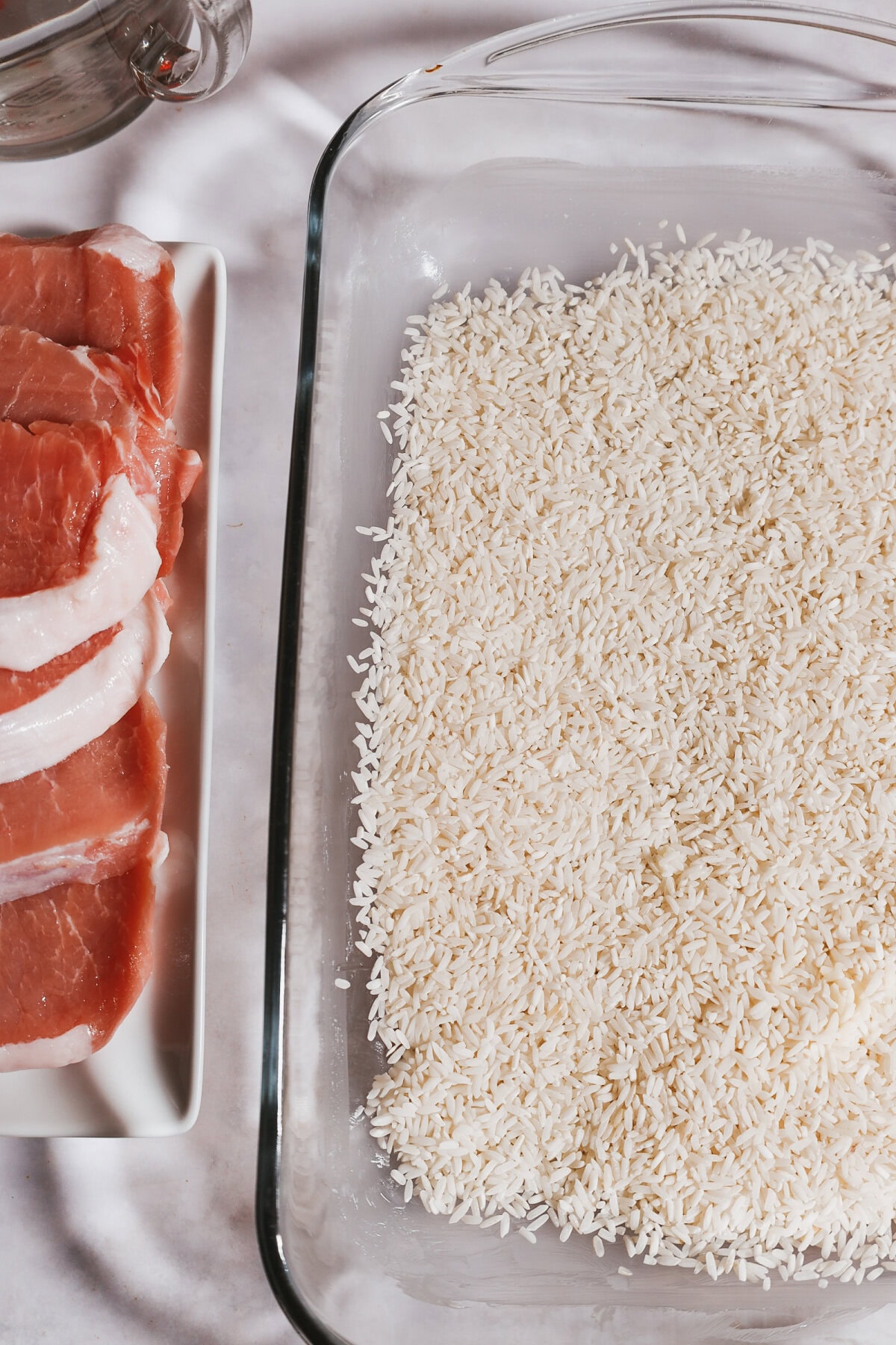 White rice spread evenly into a glass 9x13 baking pan.