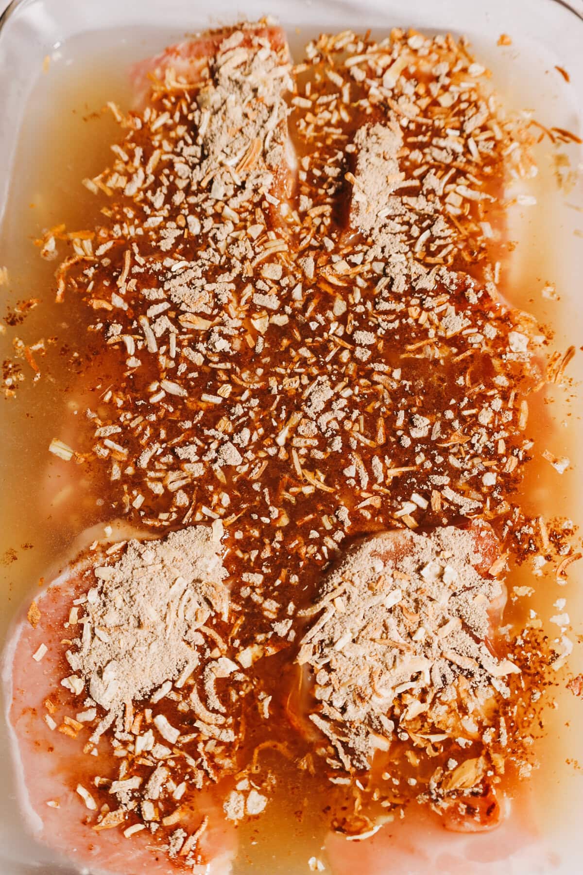 Lipton onion soup sprinkled on top of pork chops with water, rice, and butter in a glass 9x13 baking dish.
