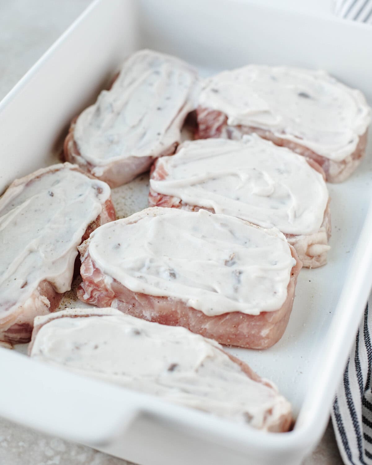 Cream of mushroom soup spread evenly on top of boneless pork chops.