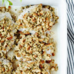 Stuffing mix combined with broth and spread on top of pork chops in a baking pan.