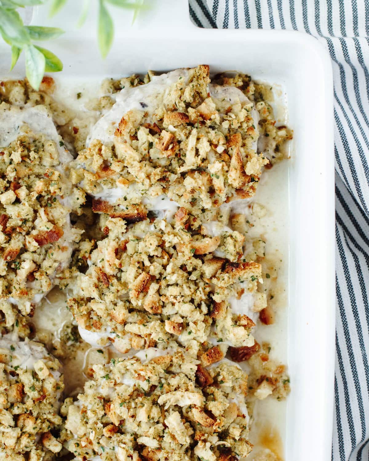 Stuffing mix combined with broth and spread on top of pork chops in a baking pan.