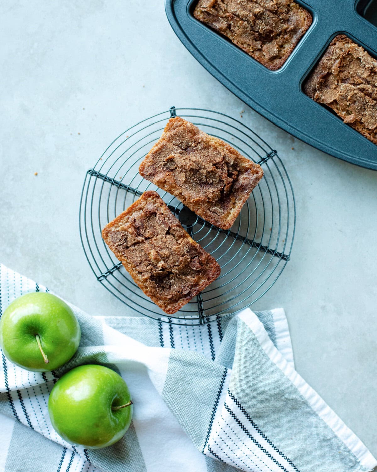 Mini loaves of quick bread with apples and cinnamon cooling on a wire rack.