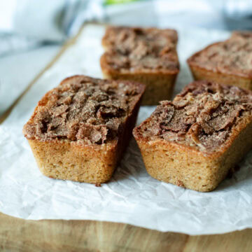 Mini loaves of snickerdoodle apple quick bread on a wood cutting board.