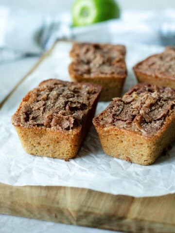 Mini loaves of snickerdoodle apple quick bread on a wood cutting board.