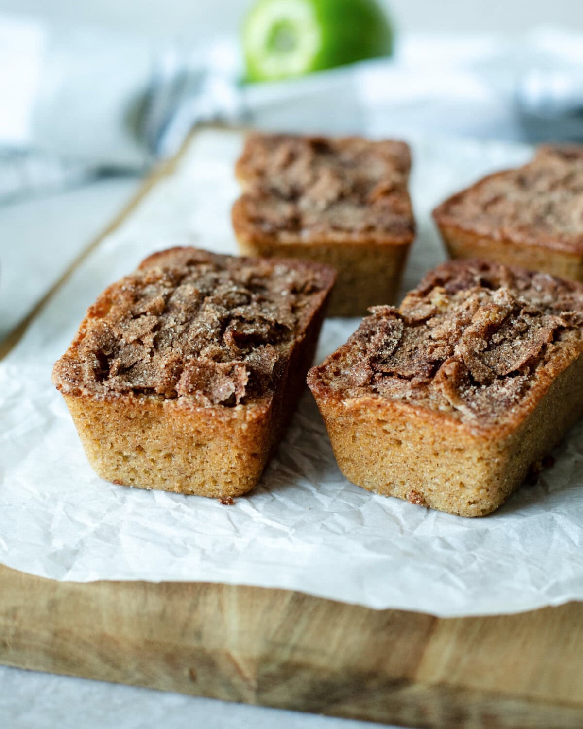 Mini loaves of snickerdoodle apple quick bread on a wood cutting board.
