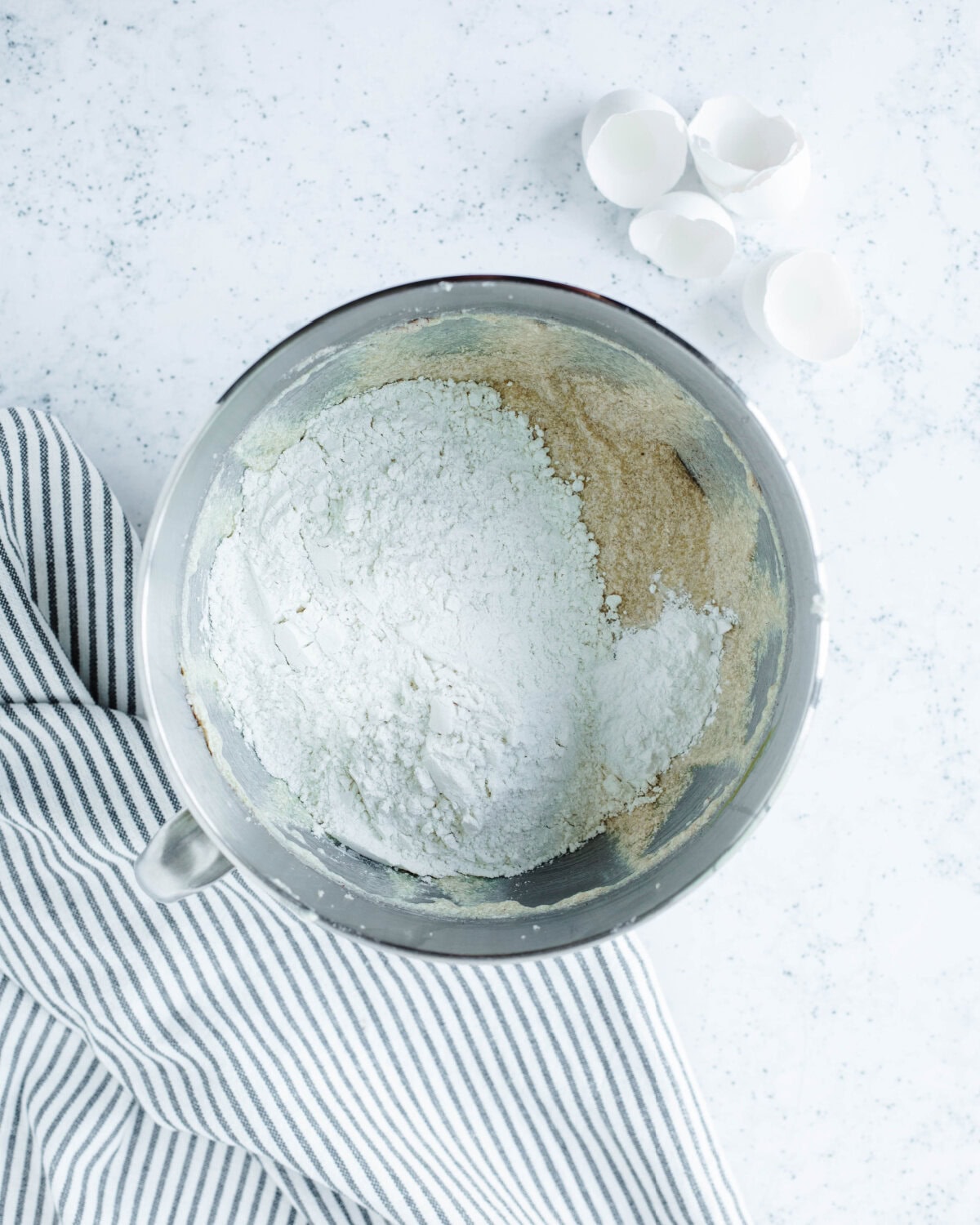 Flour and baking powder folded into bread batter in a mixing bowl.