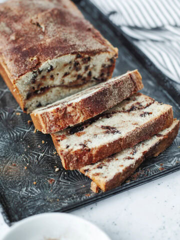 Baked loaf of snickerdoodle bread sliced and ready to serve from a serving tray.