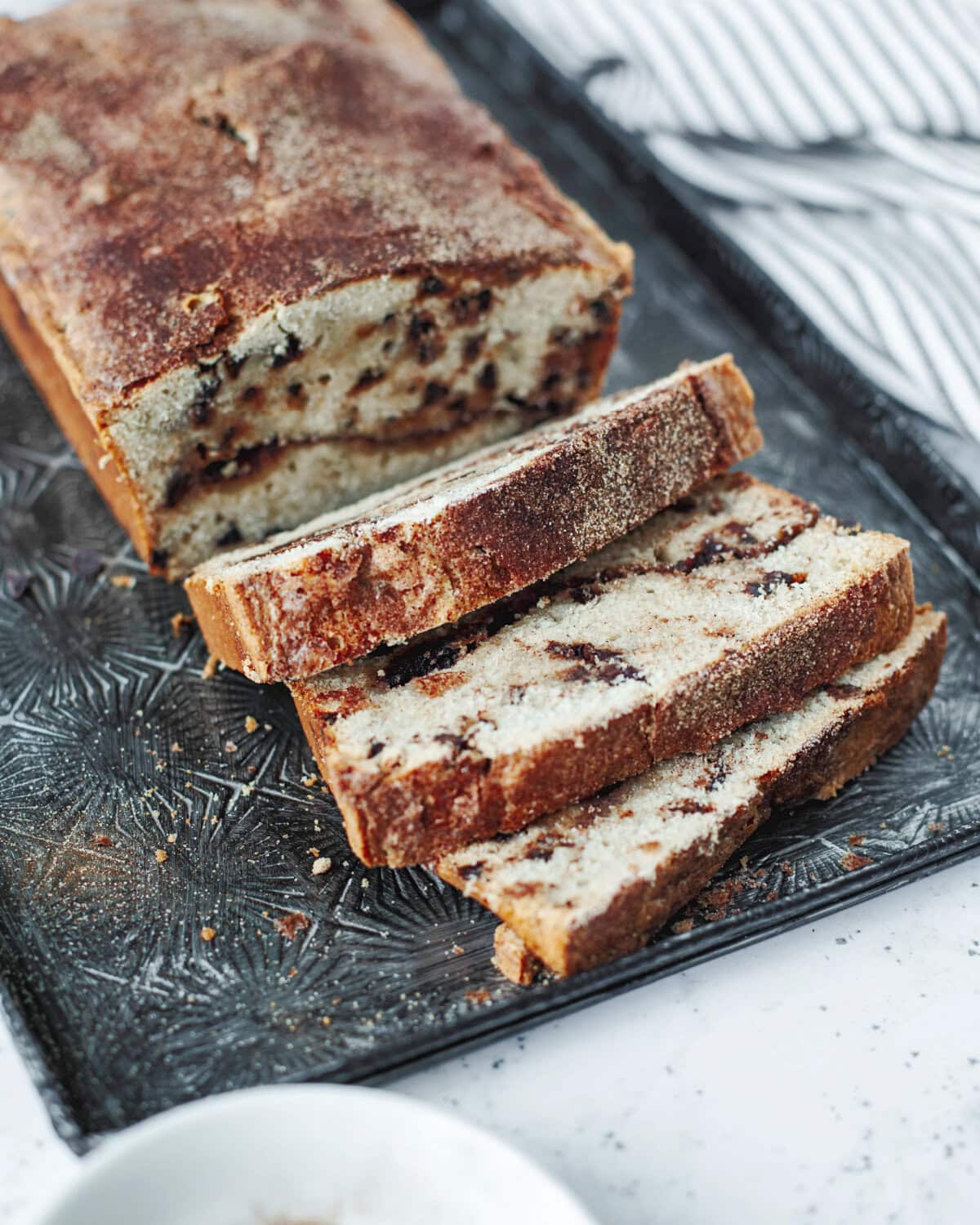 Baked loaf of snickerdoodle bread sliced and ready to serve from a serving tray.