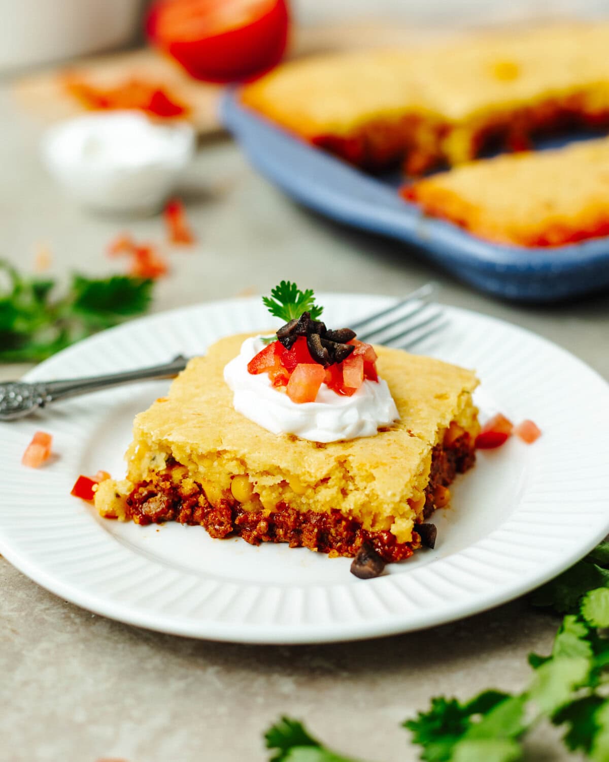 taco cornbread slice on a white plate with toppings.