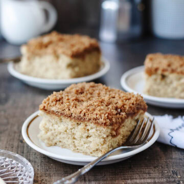 A slice of banana coffee cake on a small white plate with a fork.