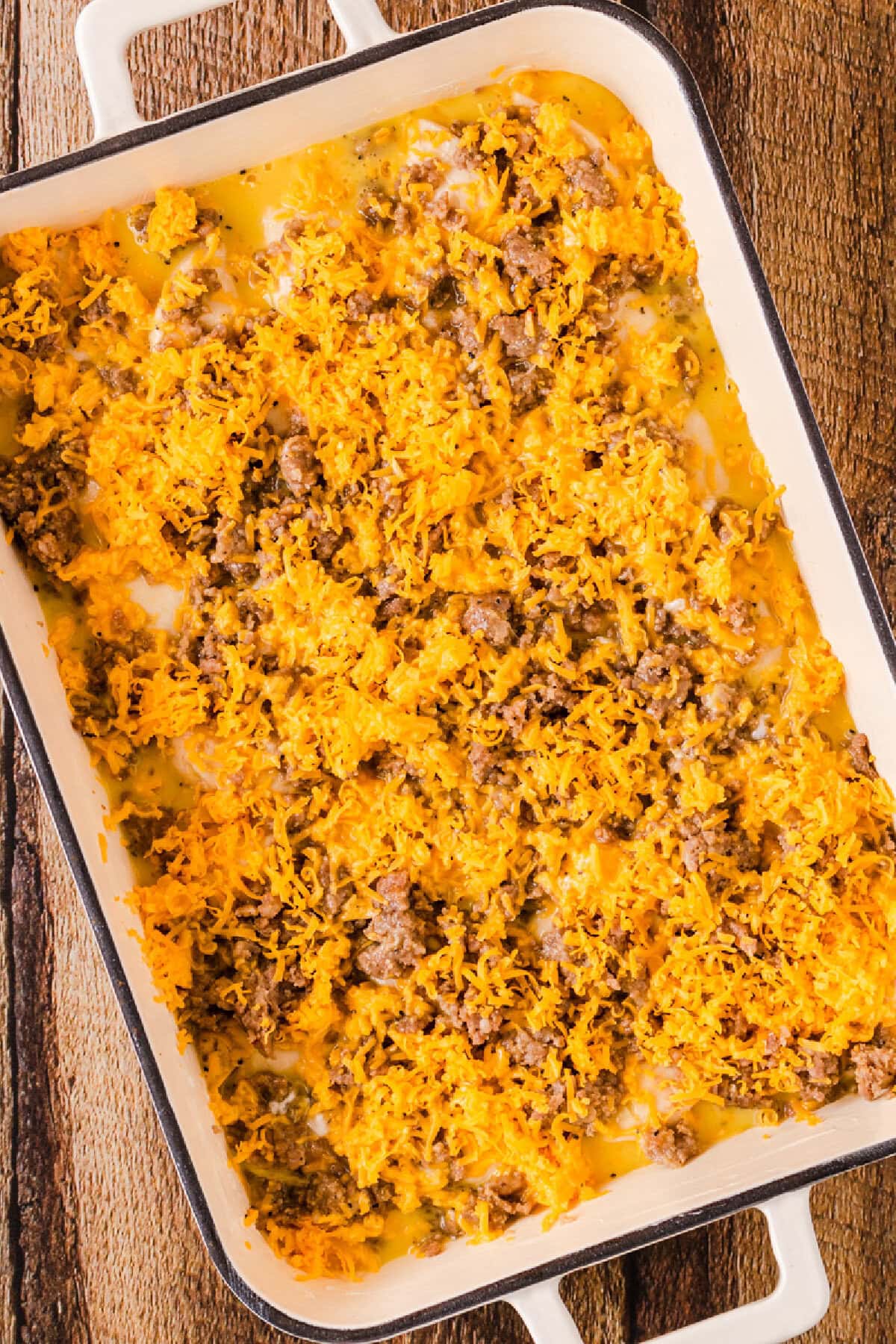 Shredded cheese sprinkled on top an egg mixture, crumbled breakfast sausage, and biscuit pieces.
