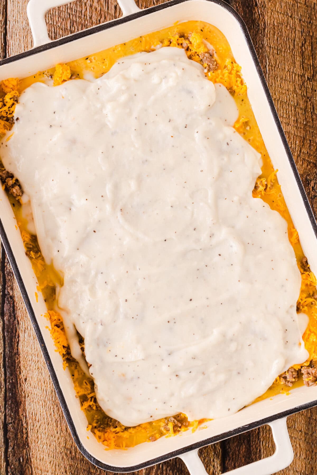 Peppered gravy spread on top of shredded cheese, egg mixture, biscuit pieces, and seasonings.