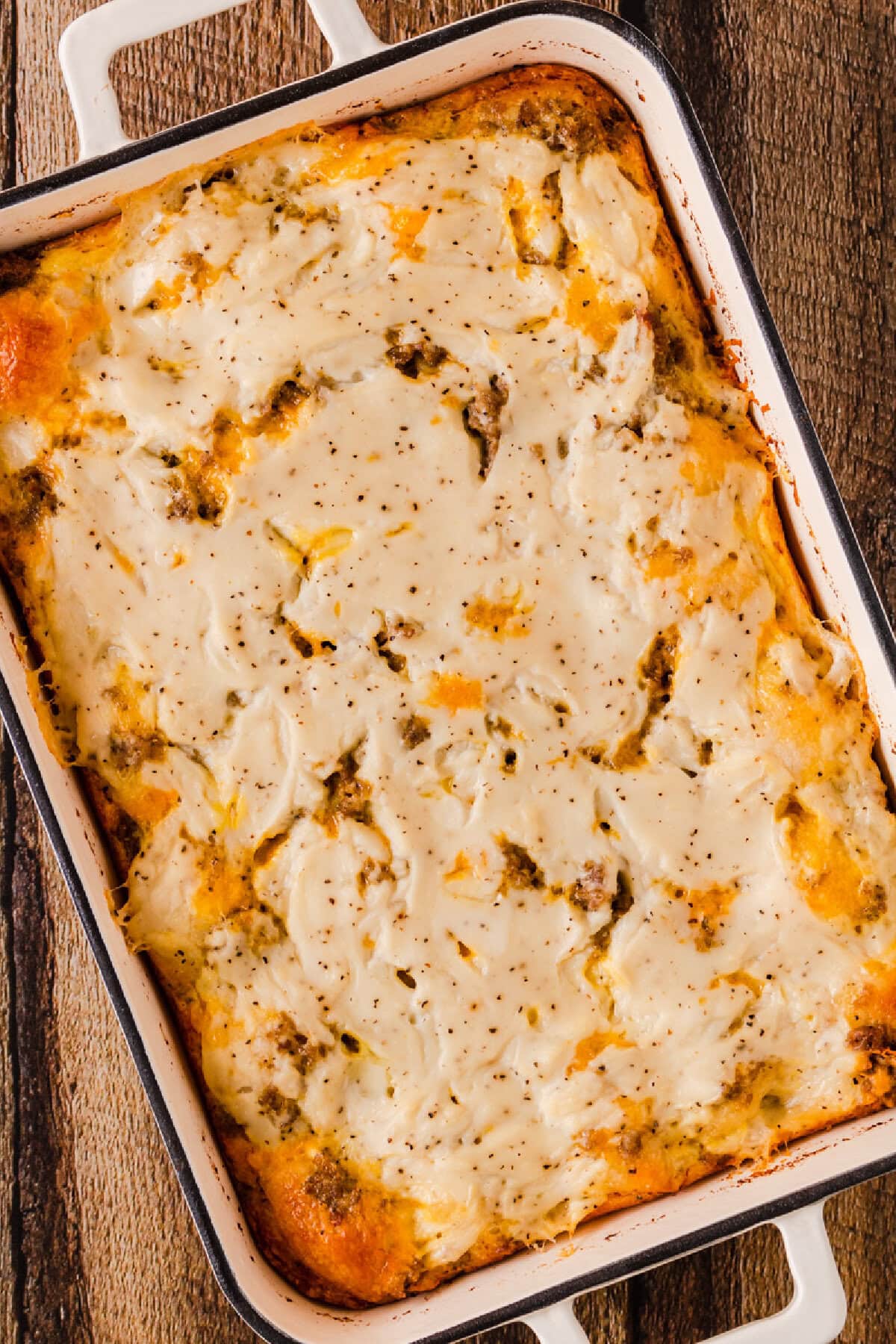 Baked biscuits and gravy casserole in a white baking pan.