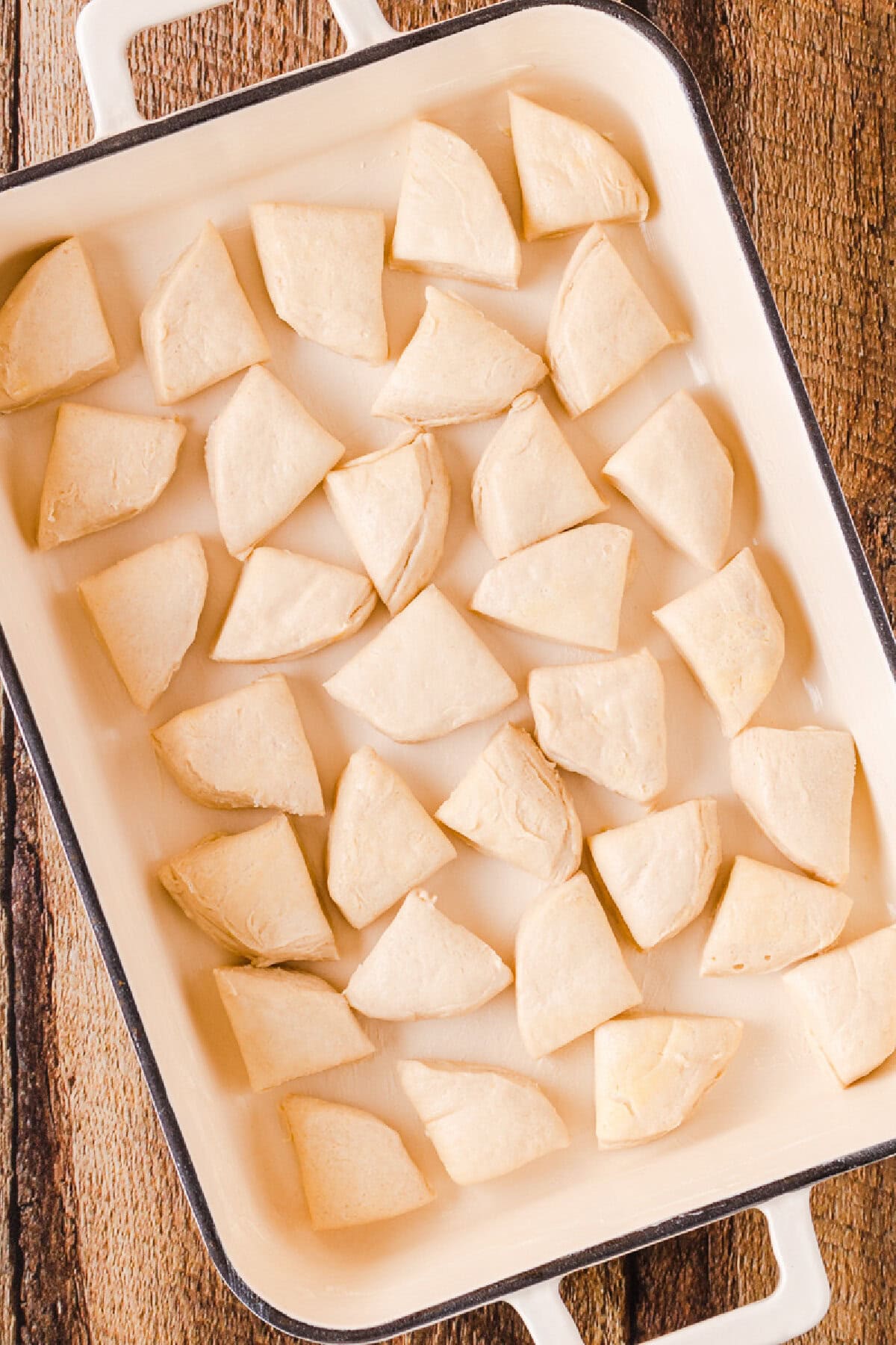 Biscuit pieces layered the bottom of a white ceramic baking dish.