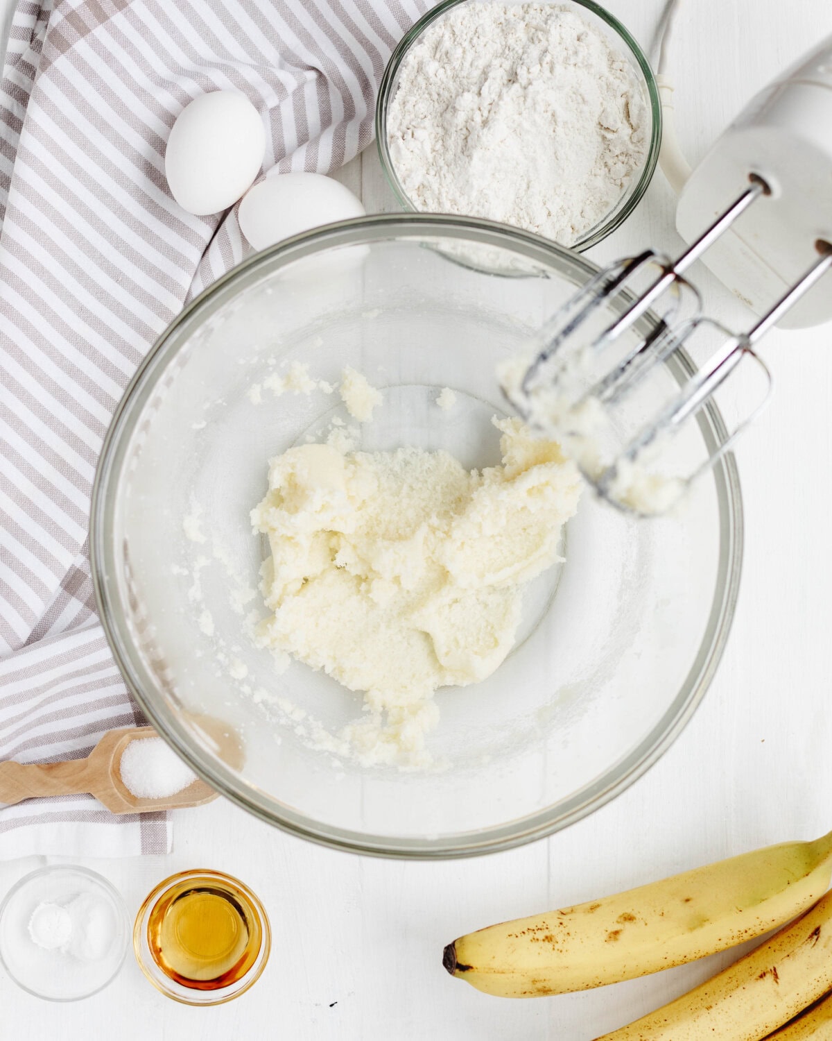 Butter and sugar creamed together in a glass mixing bowl using an electric mixer.