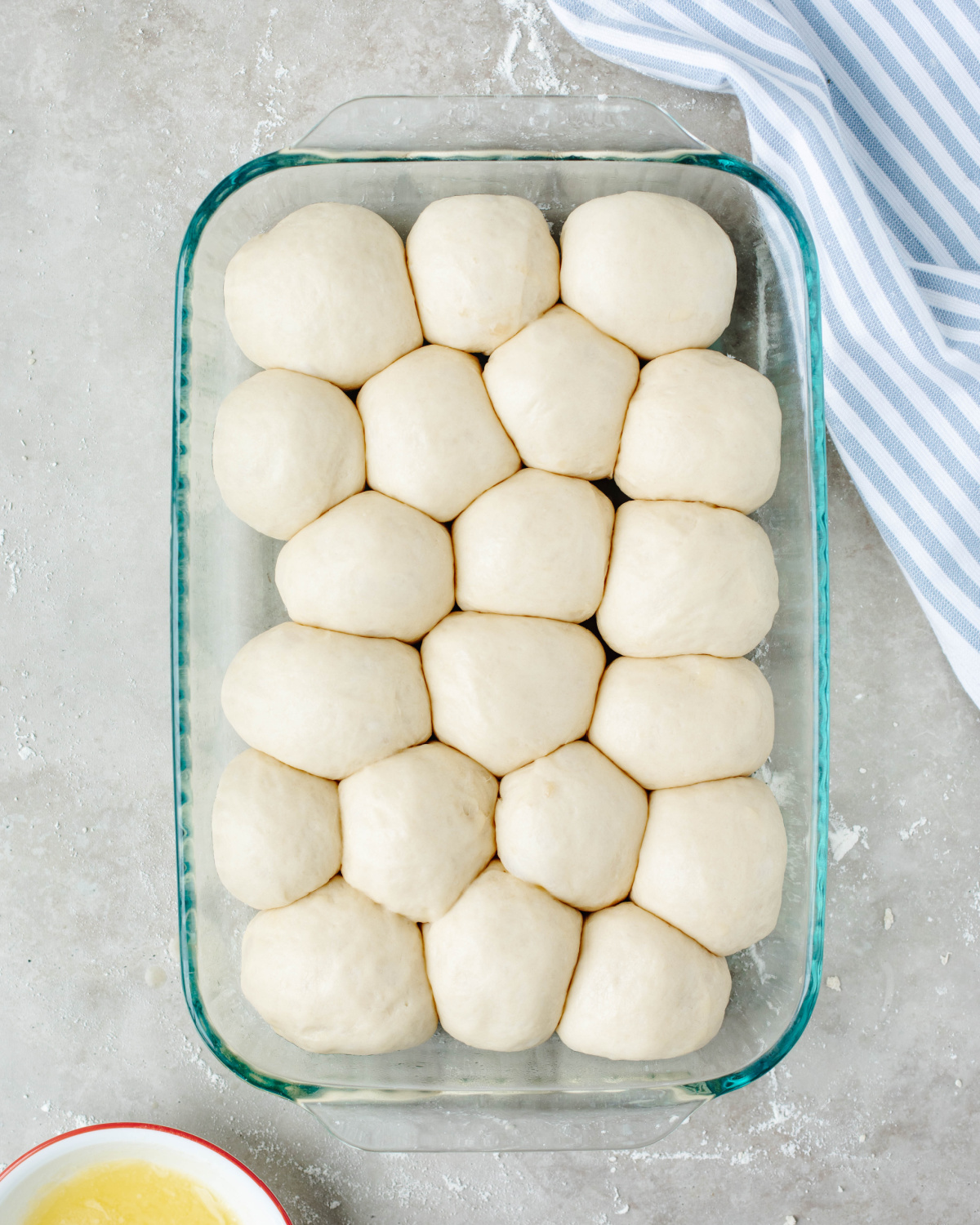 Dinner roll dough rolled into balls and placed in a greased 9x13 glass pan to rise.