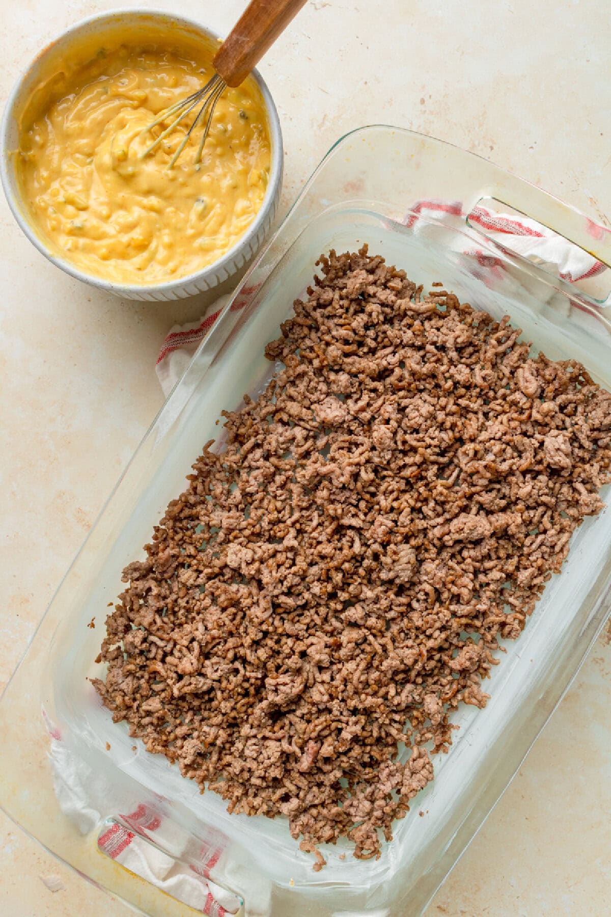 Ground beef spread into an even layer in a glass 9x13 baking pan.
