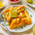 A serving of Cheeseburger French Fry Casserole on a white plate with toppings.