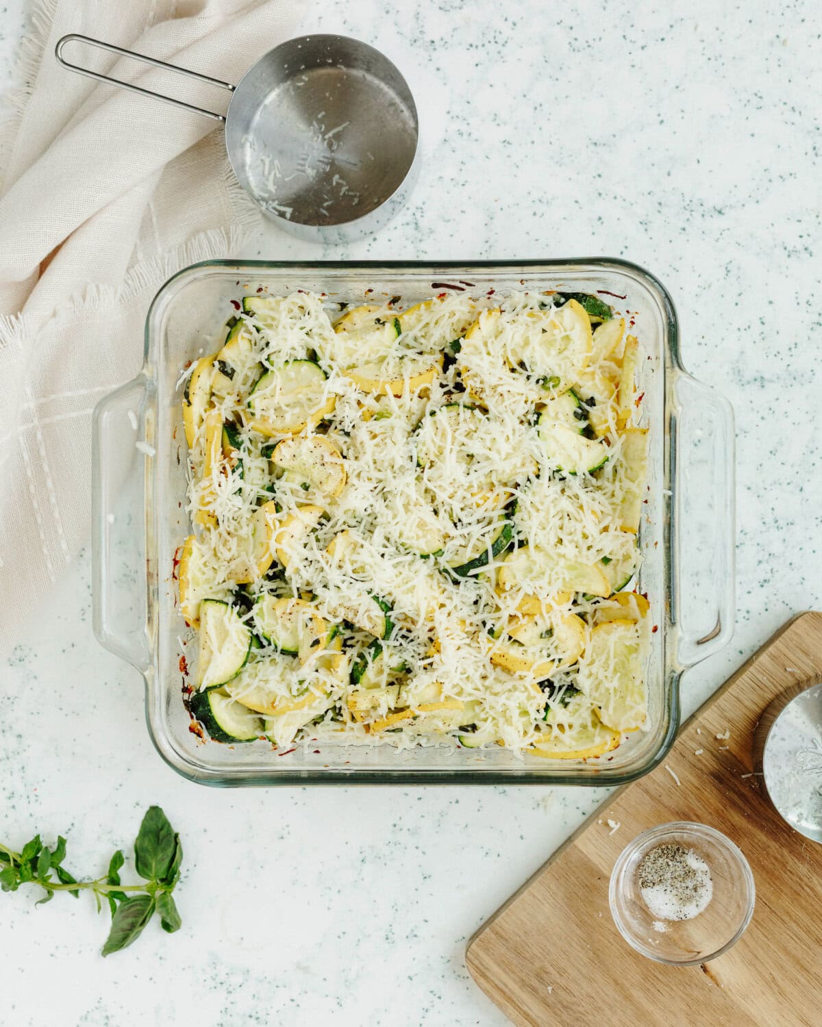 Shredded cheese sprinkled evenly on top of diced veggies in a baking pan.