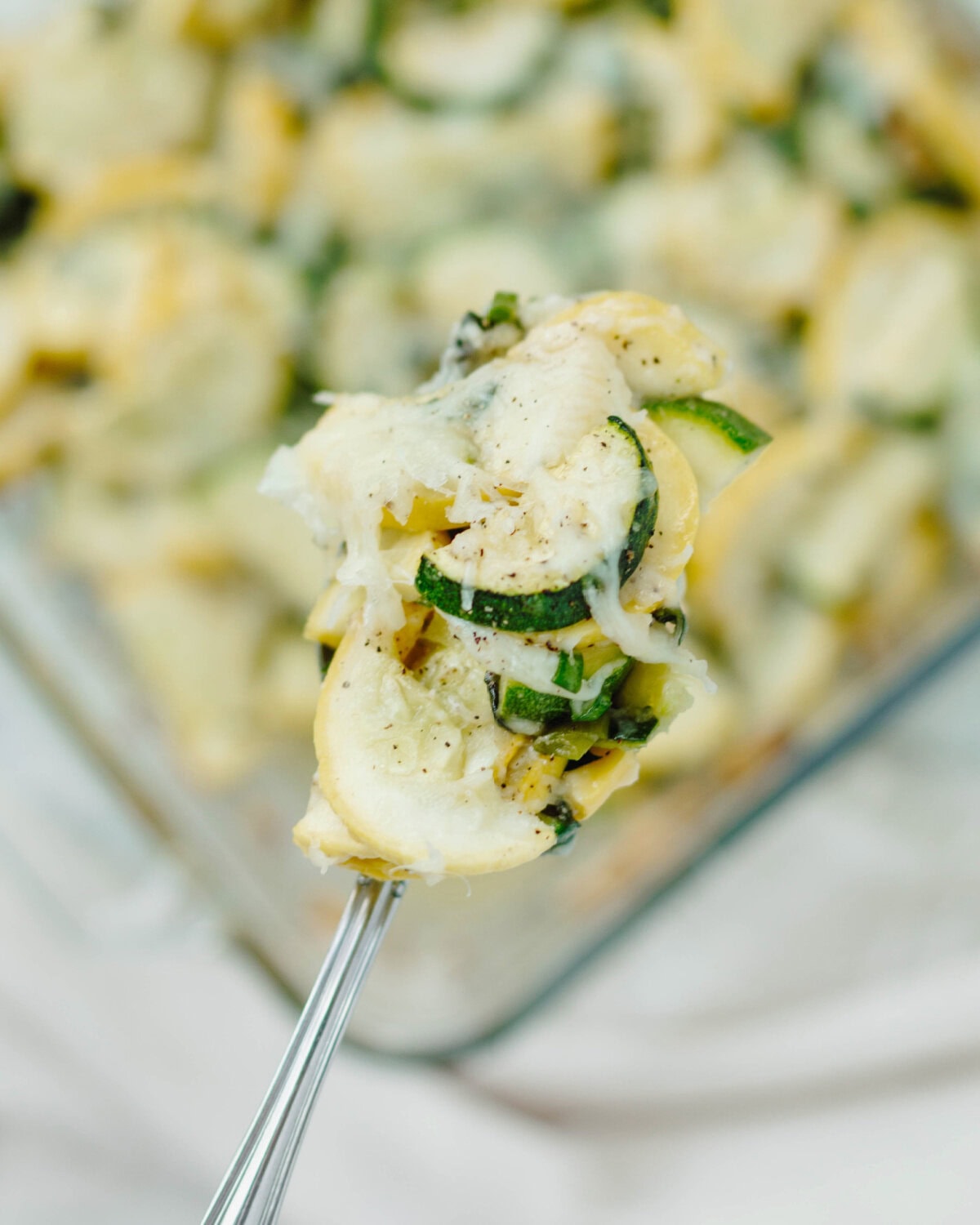 Cheesy zucchini casserole scooped up on a fork and ready to eat.