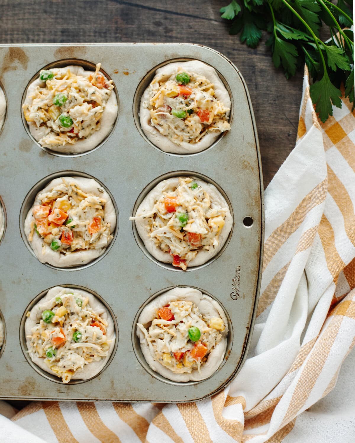 A chicken and vegetable mixture added to the center of a biscuit in a muffin cup.