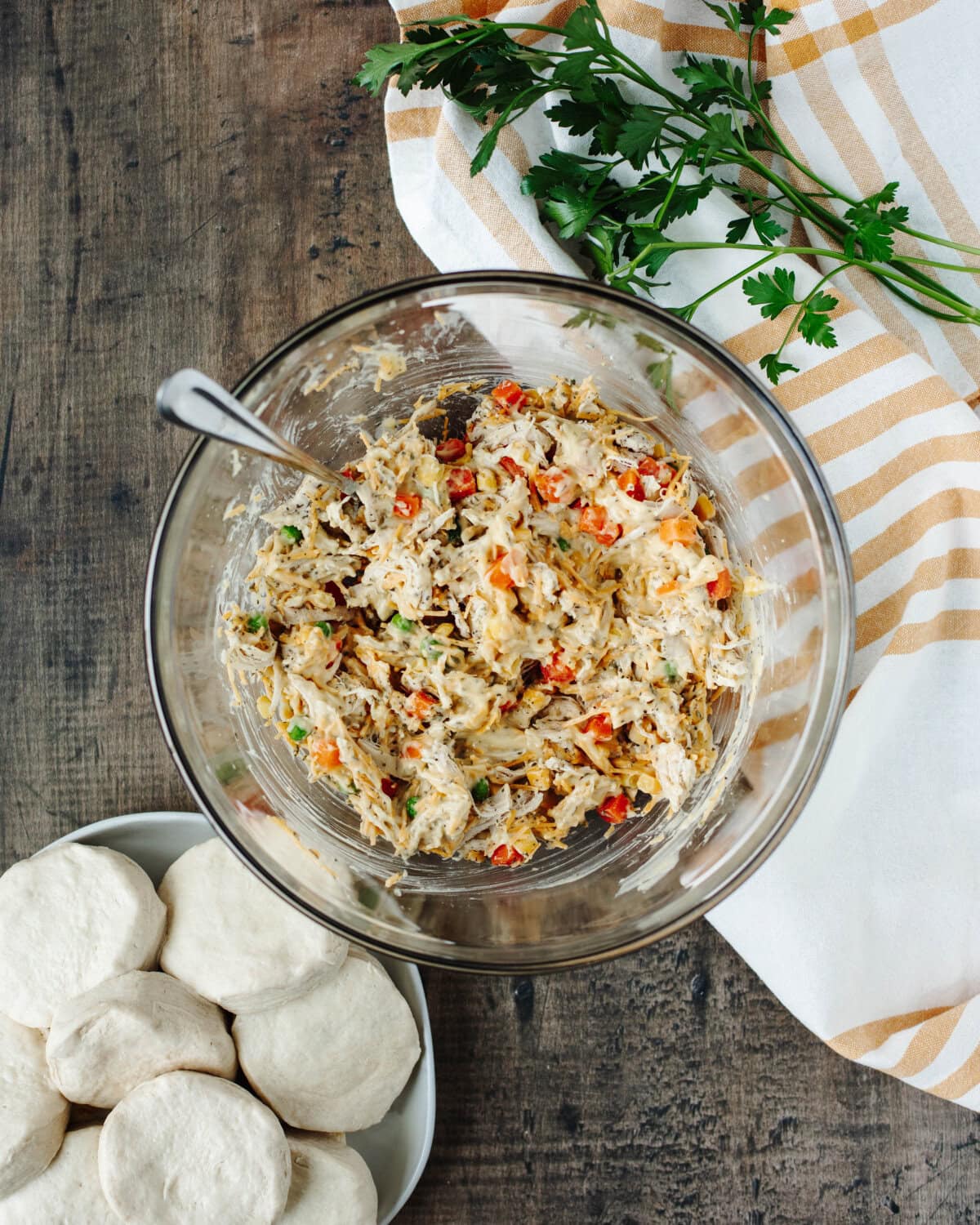 Shredded chicken, mixed vegetables, cream of chicken soup, and seasonings combined in a glass mixing bowl.