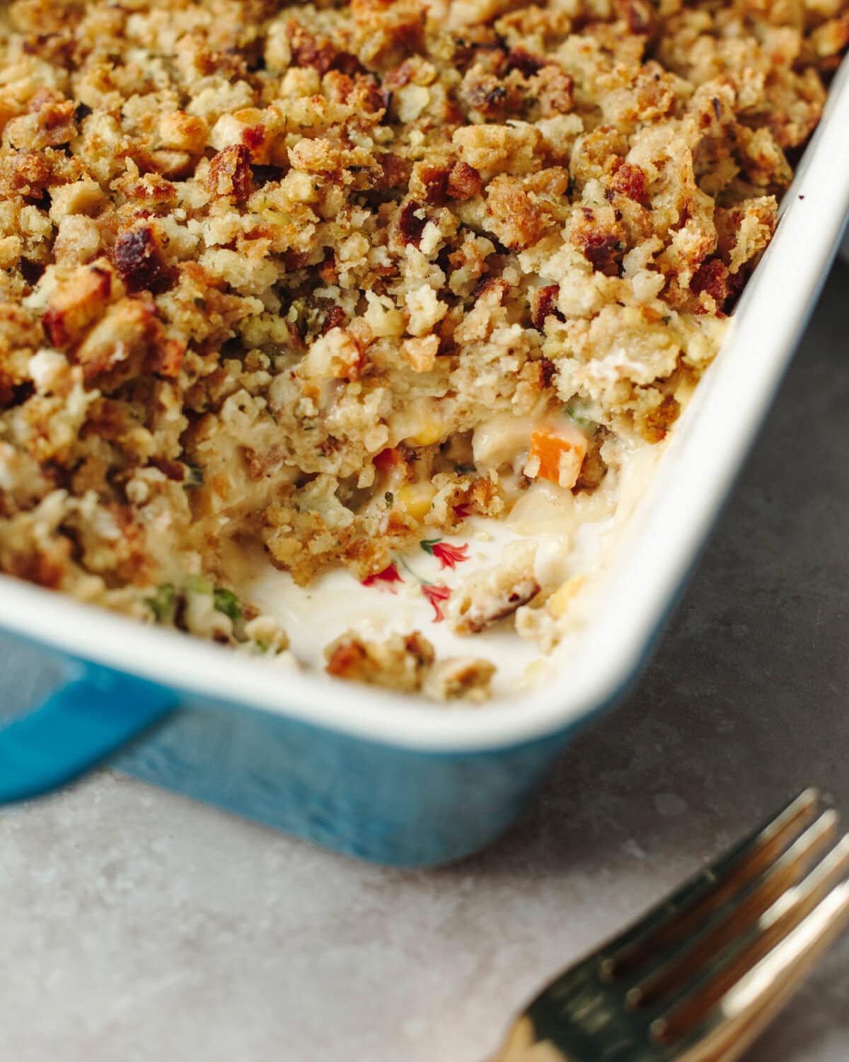 Baked stuffing topped chicken pot pie in a blue ceramic baking dish.