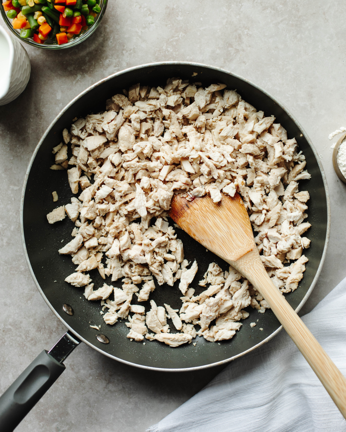 Diced chicken cooked in a black skillet until no longer pink.