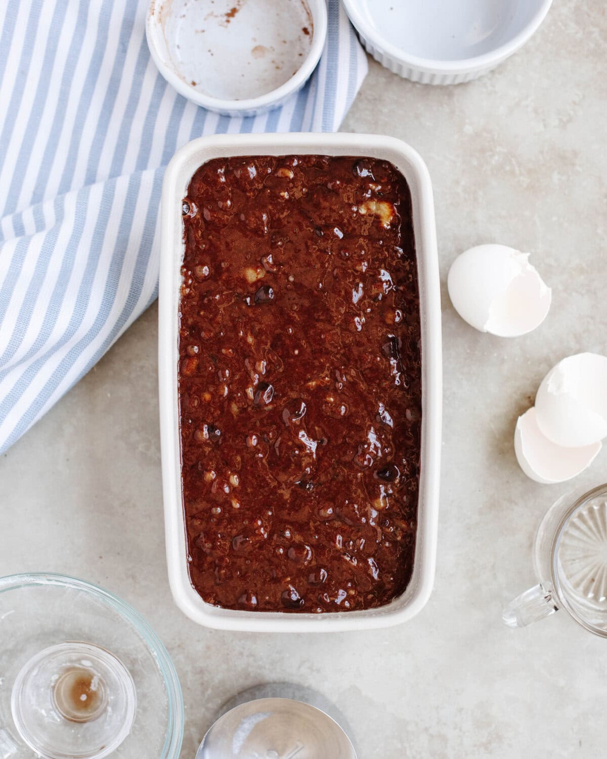 Banana bread batter spread evenly into a greased white loaf pan.