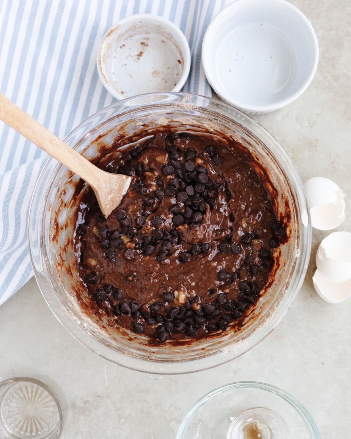 The sugar, eggs, vegetable oil, bananas, vanilla, flour, cocoa powder, baking soda, and salt combined in a glass mixing bowl.